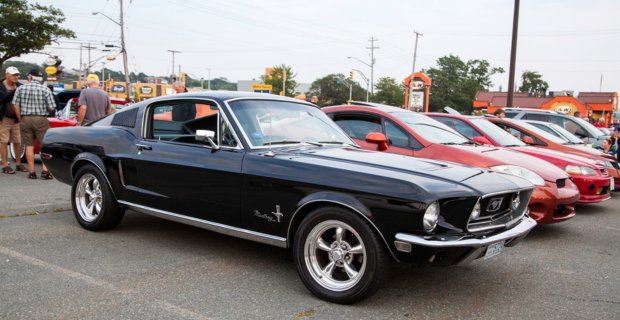 A row of collector cars lined up in the parking lot of an A&W restaurant. 