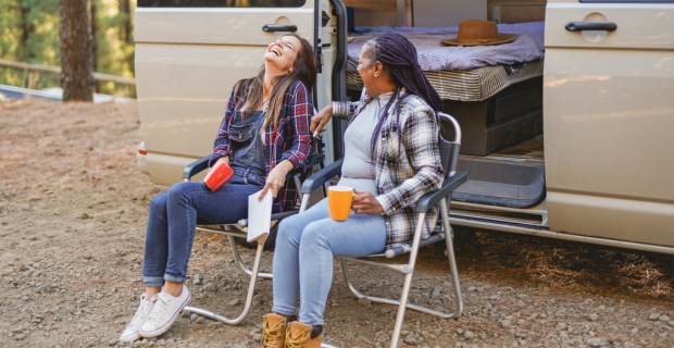 Multiracial senior women enjoy vacation in nature by their motorhome.