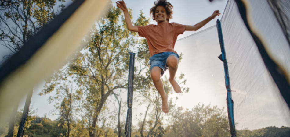 Young person bouncing and enjoying their trampoline in the summer. 