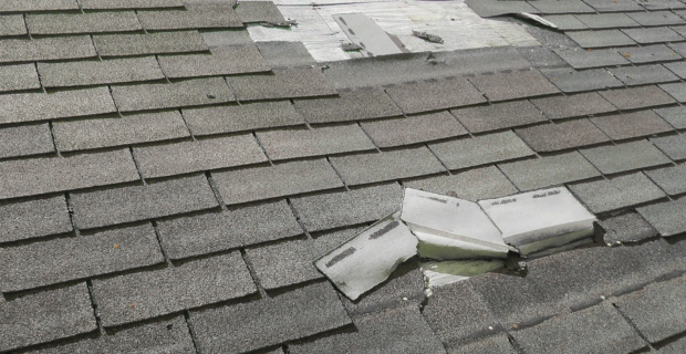 Close up of a roof with damaged tiles peeling off.