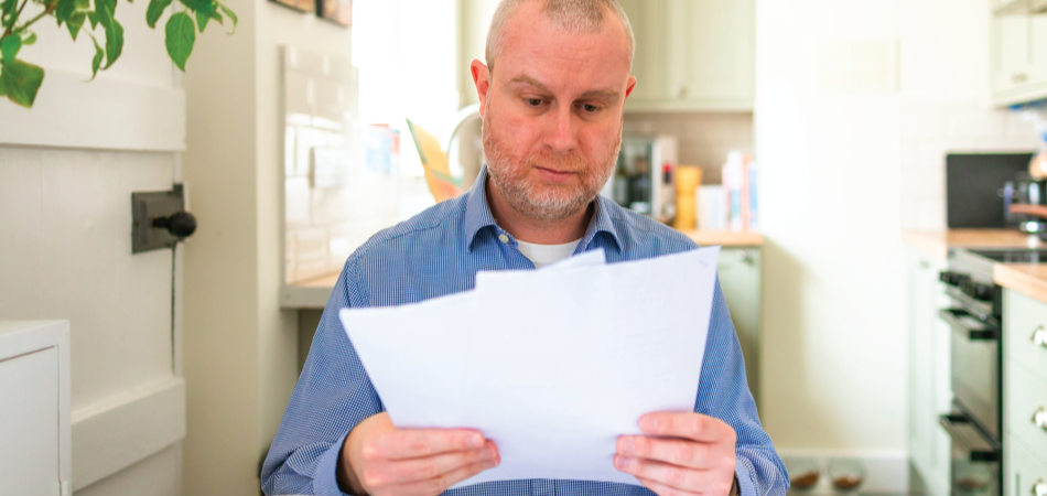 Person in a blue shirt reading papers in a kitchen.