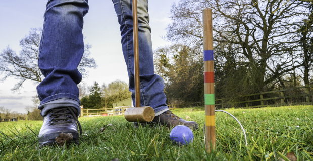 Person standing and playing croquet on grass