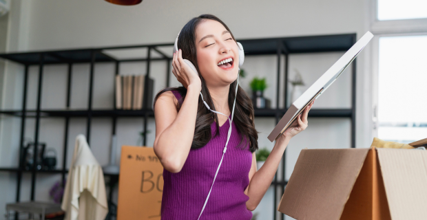 A young lady listening to music while she unpacks boxes in her rented dwelling. 