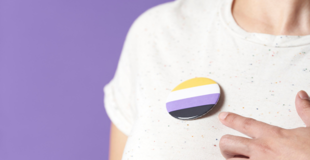 A photo of someone pointing at a progress pride pin. 