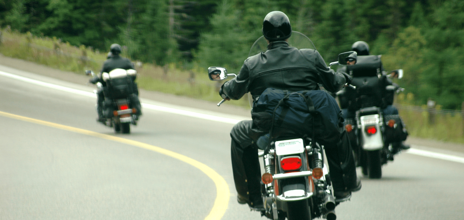 Three people riding motorcycles together on a highway.