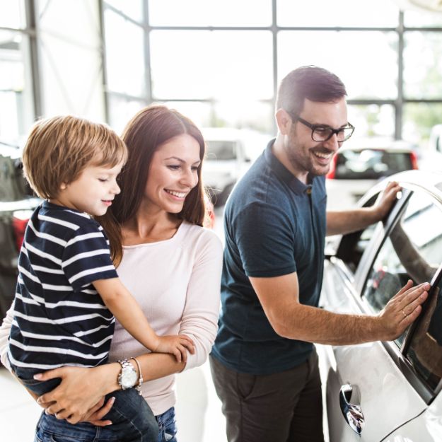 A family looks at a new vehicle inside a dealership.