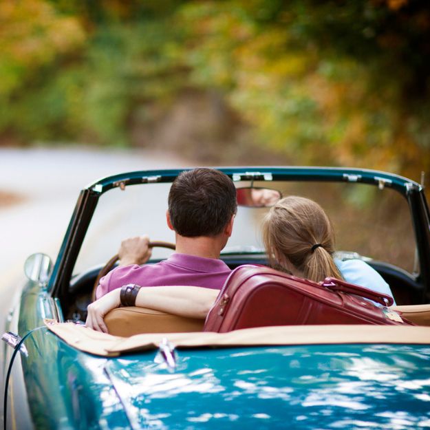 A couple in a blue convertible classic car out for a leisurely drive. 
