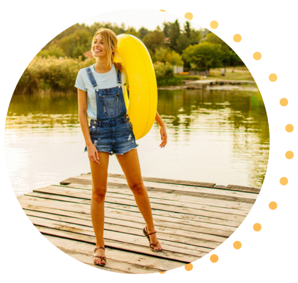 A woman holding a yellow floatie, standing on the dock at her cabin.
