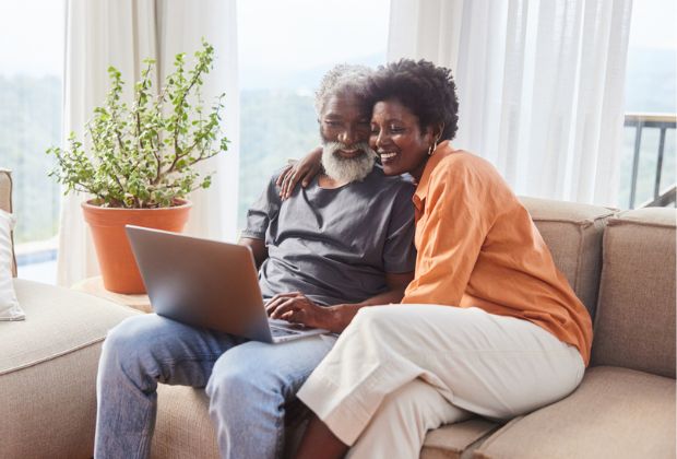 A man and woman sitting on a couch with a laptop