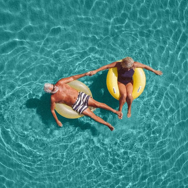 A man and a woman holding hands while relaxing on a inflatable float