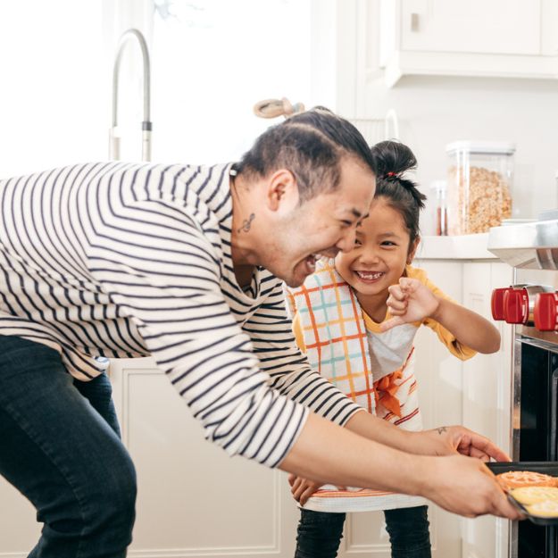 An Asian-Canadian man and his child baking cookies together in their new home in Alberta.