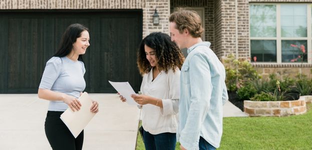 A realtor and her clients review an offer outside their house. 