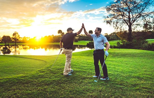 Two golfers high-five on the green.