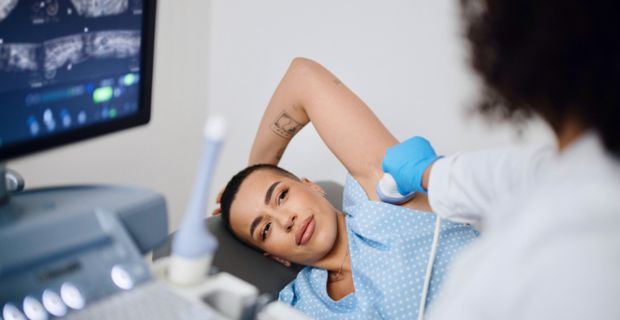 A person with short-cropped hair getting an ultrasound of their underarm.