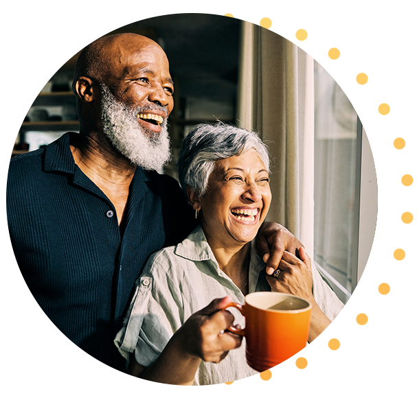 Mature couple embracing while looking out window of home 