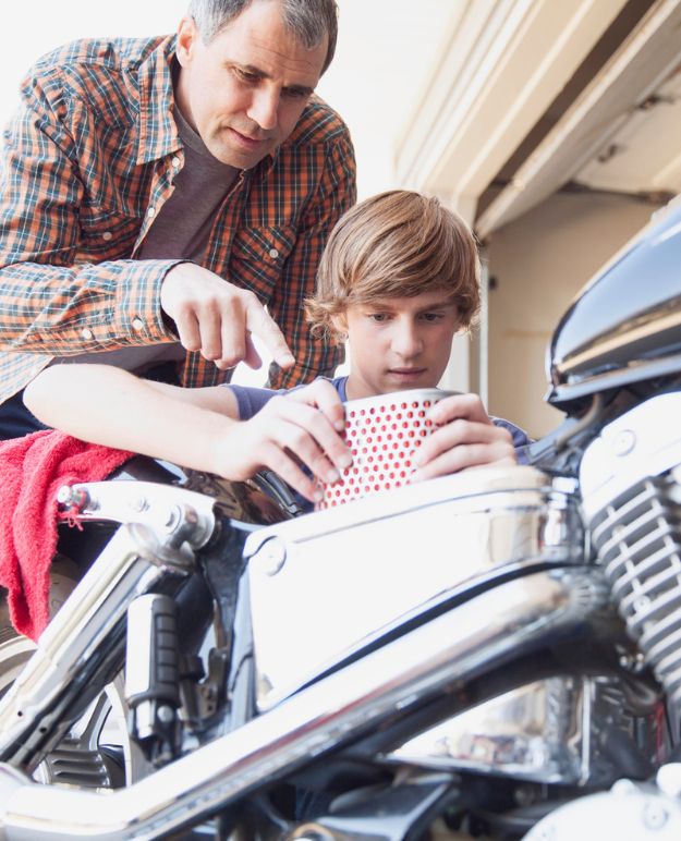 A man in his 50s, teaching his son how to maintain a bike.