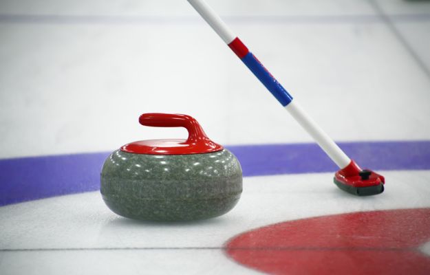 A close-up of a curling stone sliding close to the button.