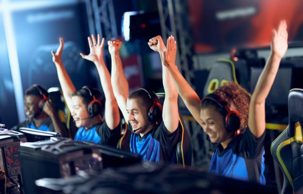 Gamers at an event raise their arms in triumph.