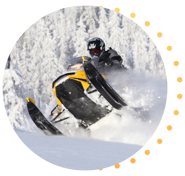 A snowmobiler catching air as they ride over a small hill.