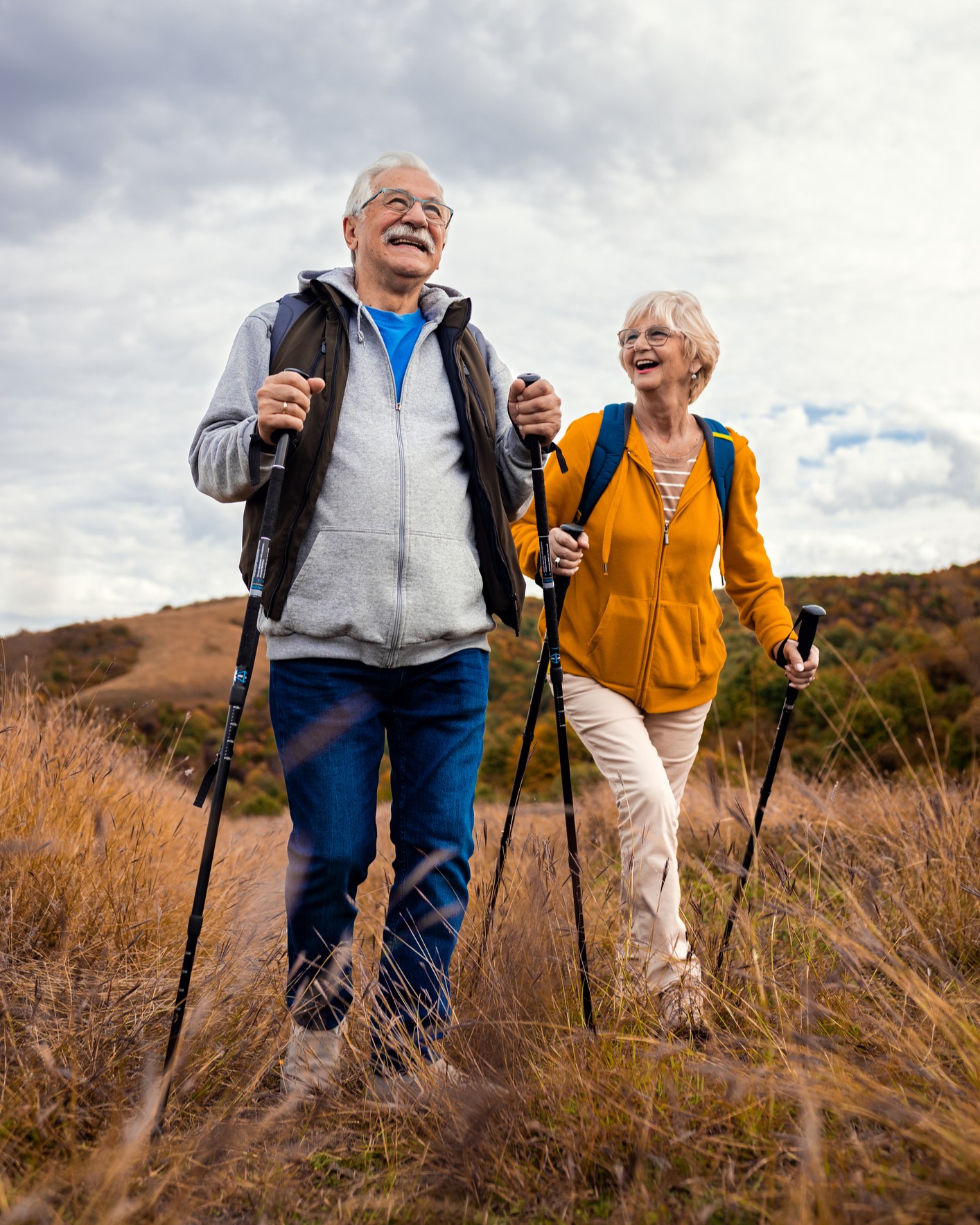 An active senior couple hiking with walking sticks