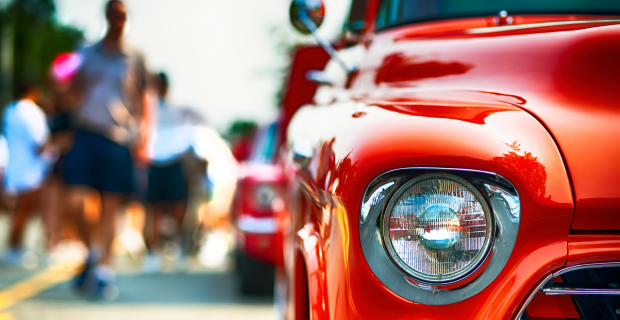 Classic cars on display at a classic car show in Canada with people walking by to view the cars during the summer.