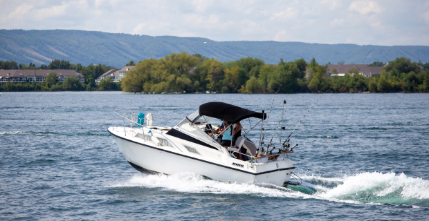 Motorboat cruising on a calm Canadian lake near forested shoreline.  