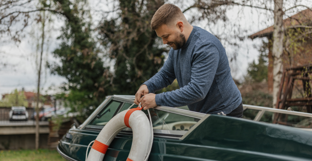Man securing a lifebuoy on a boat, emphasizing safety and preparedness for boating insurance.  