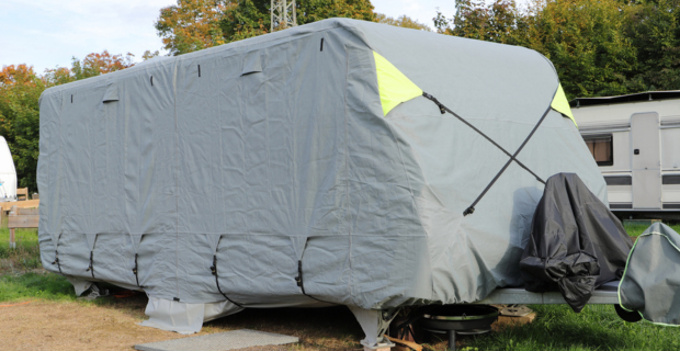 A winterized RV is protected with a gray weatherproof cover showing an example of winterizing your RV.