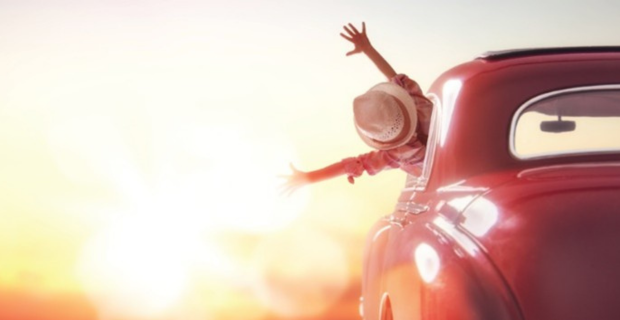 A young woman is happy and proud behind the wheel of her Beetle
