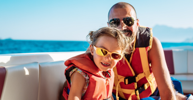 A father and daughter on their boat practicing boating safety in Canada. 