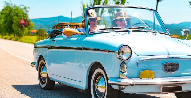 A couple driving in a Robin blue convertible collector car on a beautiful sunny day. The wind gently tousles their hair as they enjoy the open road and the warmth of the sun. The image captures the carefree spirit of a leisurely drive in a classic car, evoking a sense of nostalgia and the joy of summertime adventures.